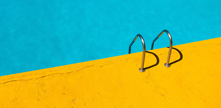 Picture of a swimming pool, contrasting colours of bright yellow poolside and blue water.