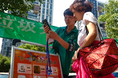 A volunteer shows a Beijing resident how to use apps to sort garbage on July 26, 2019 (WANG XIANG)